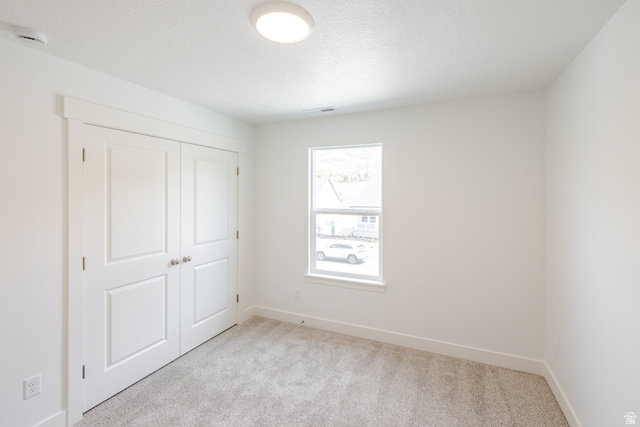 4816 Heartwood Road, Unit 423 Mapleton, UT 84664 - Photo 17 of 21 Unfurnished bedroom featuring light carpet, a closet, and a textured ceiling