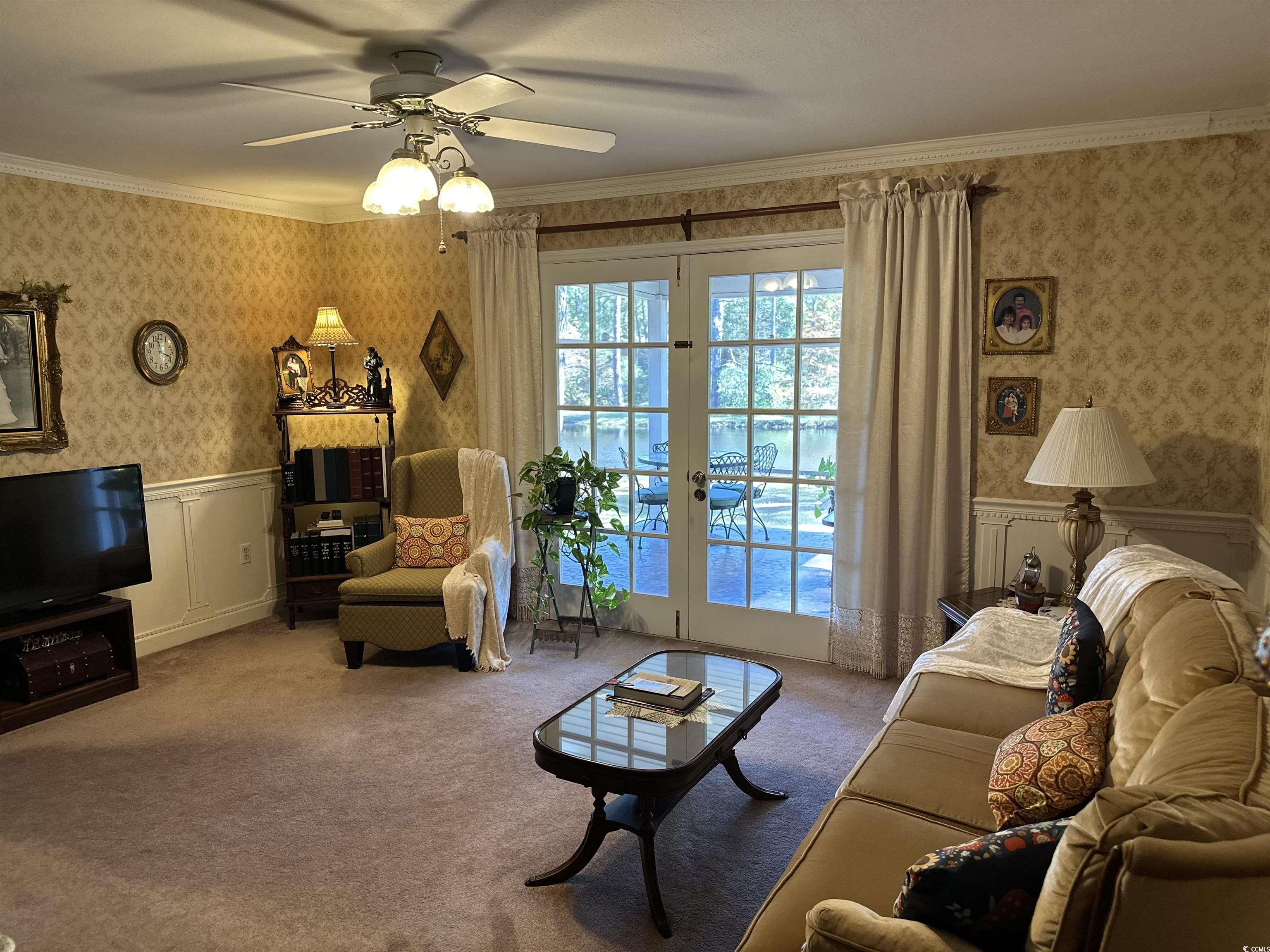 2840 Pennyroyal Road Georgetown, SC 29440 - Photo 24 of 36 Den area with wallpapered walls, crown molding, wainscoting, ceiling fan, and carpet flooring