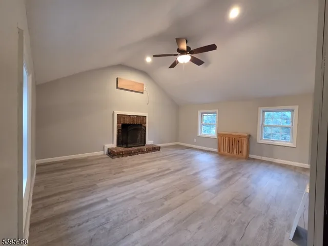 a view of empty room with wooden floor and fireplace