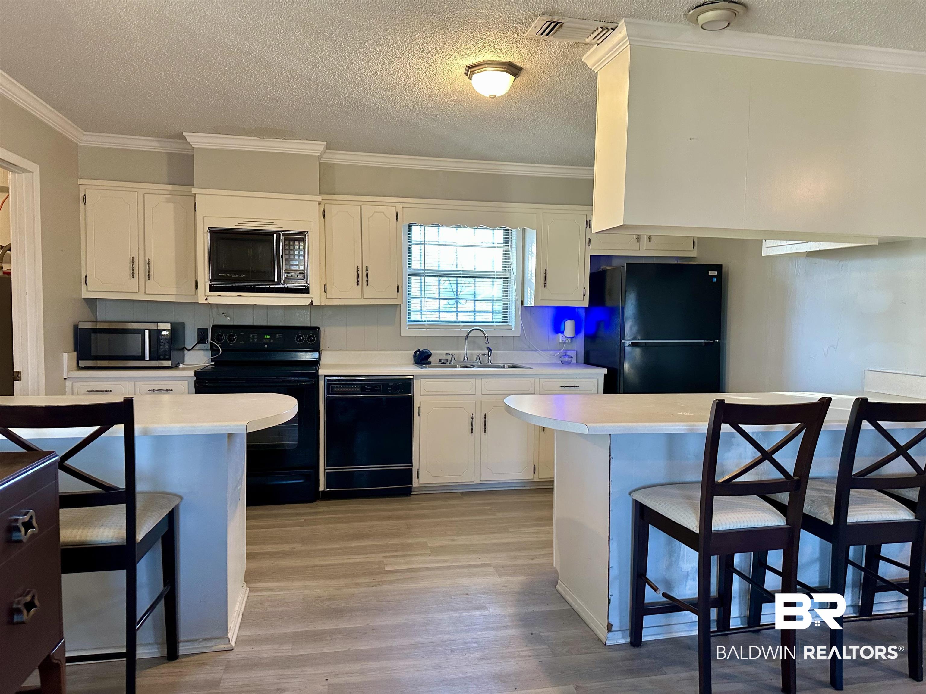 3451 Kirkland Road Brewton, AL 36426 - Photo 3 of 17 Kitchen featuring white cabinets, a kitchen breakfast bar, sink, and black appliances