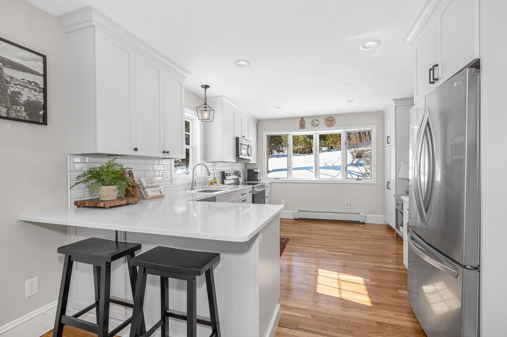 430 West Street Reading, MA 01867 - Photo 8 of 35 a kitchen with stainless steel appliances granite countertop a refrigerator a sink a stove and white cabinets with wooden floor