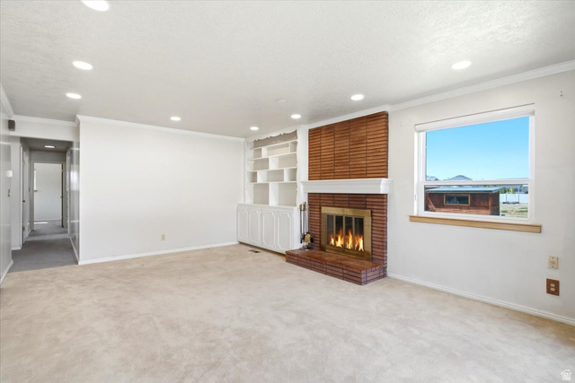 2252 West 800 North Clinton, UT 84015 - Photo 5 of 38 Living space featuring a brick fireplace with a white mantel, built-in shelving, recessed ceiling lights, a window, and light-toned carpet flooring