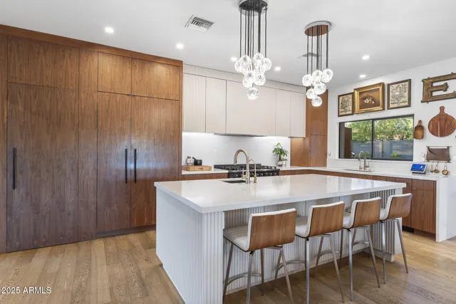 a kitchen with stainless steel appliances kitchen island granite countertop a table chairs in it and wooden floors
