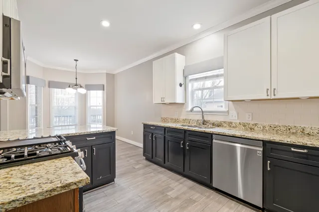a kitchen with granite countertop a sink a stove a counter space and cabinets