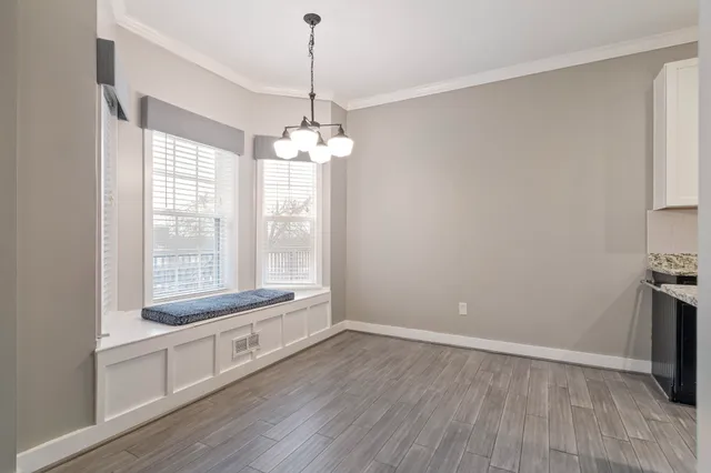 a view of an empty room with chandelier and wooden floor