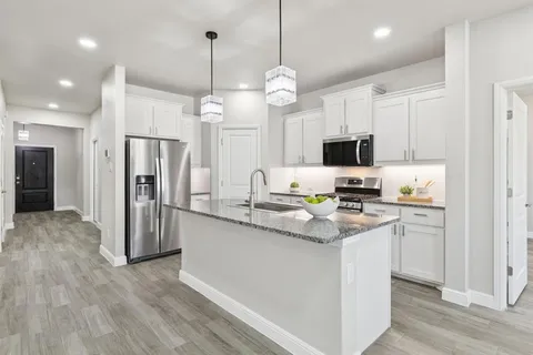 a kitchen with stainless steel appliances granite countertop a refrigerator a stove a sink and a chandelier