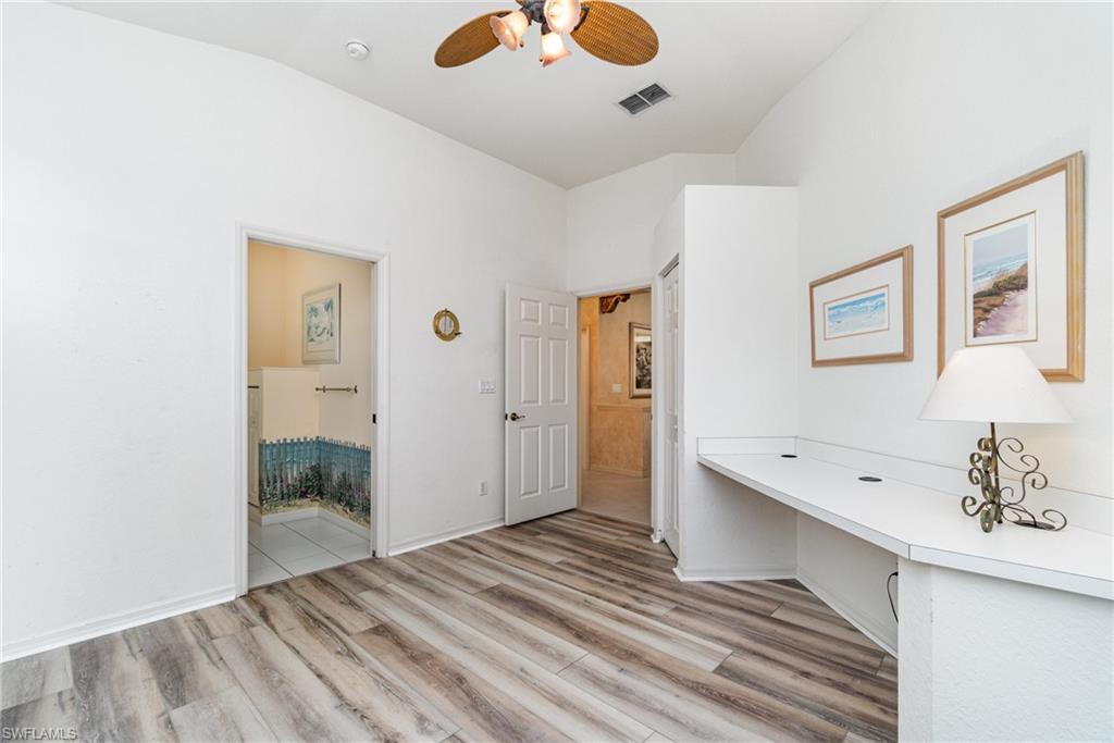 10274 Cape Roman Road, Unit 102 Estero, FL 34135 - Photo 19 of 36 a view of a hallway to a bedroom with wooden floor and a bathroom