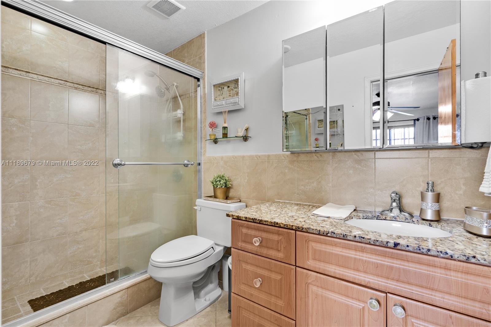 627 West 68th Street, Unit 627 Hialeah, FL 33014 - Photo 28 of 31 a bathroom with a granite countertop sink a toilet and shower