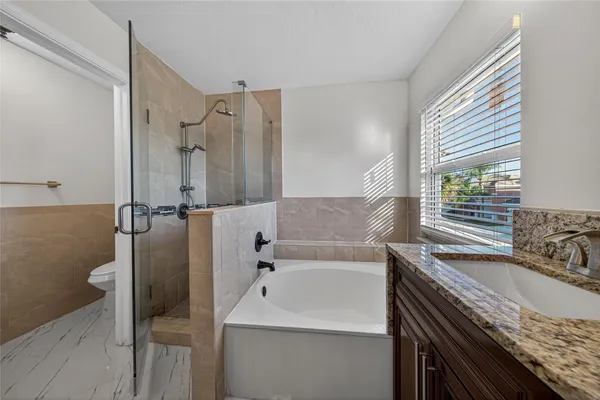a bathroom with a granite countertop sink and a bathtub