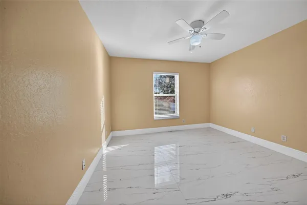 an empty room with windows and fan