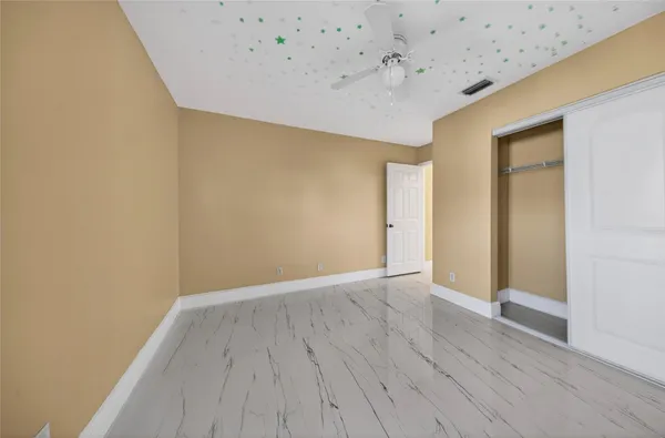 a view of an empty room with closet and a chandelier fan