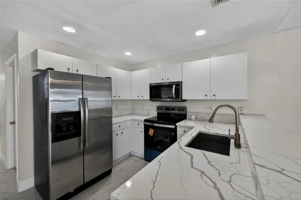 a kitchen with stainless steel appliances a refrigerator sink and microwave