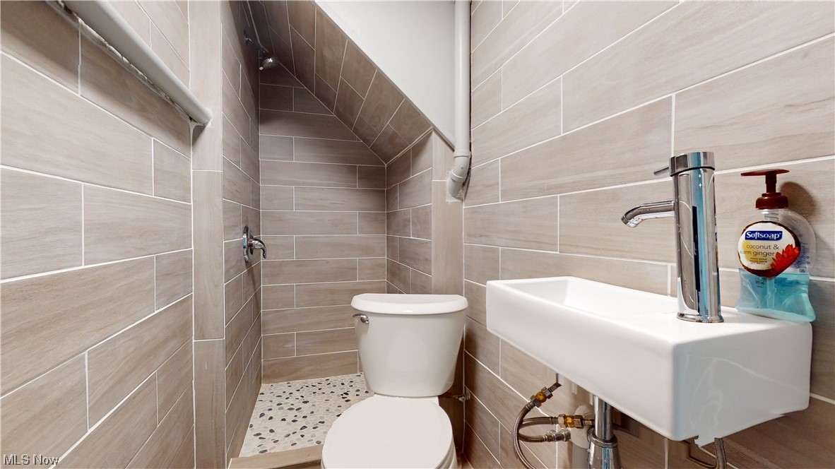 1976 Ridgewood Road Akron, OH 44313 - Photo 29 of 35 Bathroom featuring toilet, tile walls, sink, and a tile shower