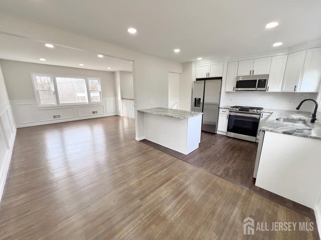 1273 Brookside Road Piscataway, NJ 08854 - Photo 12 of 33 a kitchen with stainless steel appliances granite countertop a stove top oven a sink dishwasher and a refrigerator with wooden floor