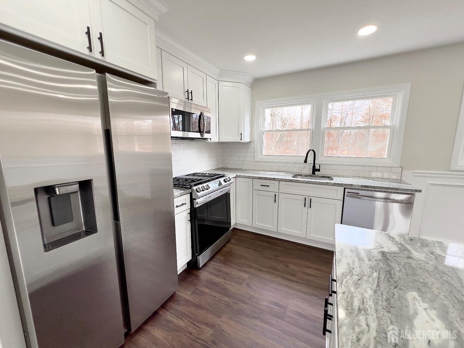 1273 Brookside Road Piscataway, NJ 08854 - Photo 14 of 33 a kitchen with stainless steel appliances granite countertop a refrigerator a sink a stove and white cabinets with wooden floor