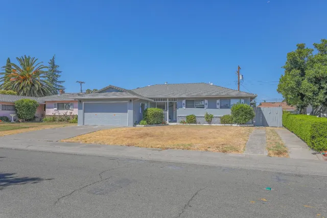 a front view of house with yard and trees in the background