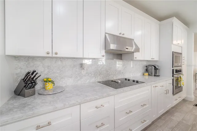 a kitchen with stainless steel appliances granite countertop a refrigerator a sink dishwasher a stove and white countertops with wooden floor