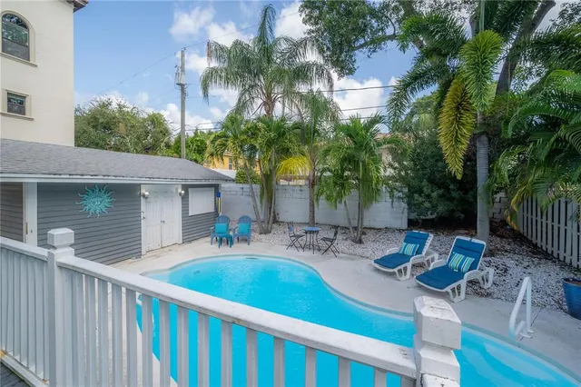 a view of a backyard with table and chairs potted plants and palm tree