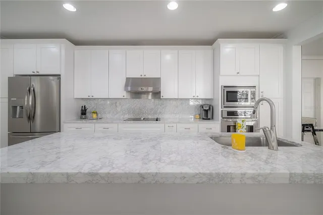 a kitchen with a stove a faucet a sink and living room view