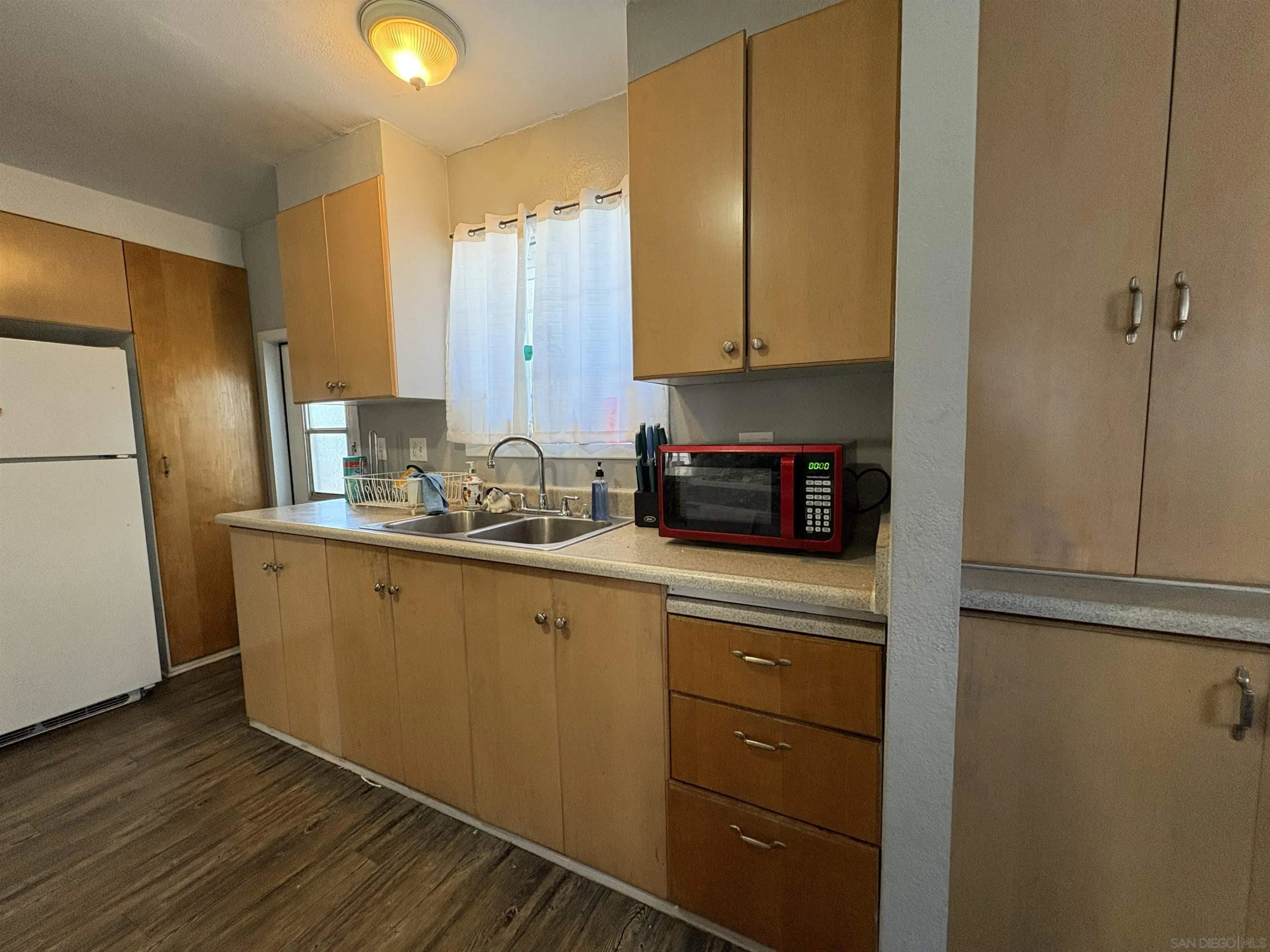402 63rd Street, Unit 99 San Diego, CA 92114 - Photo 7 of 15 a kitchen with a refrigerator sink and cabinets