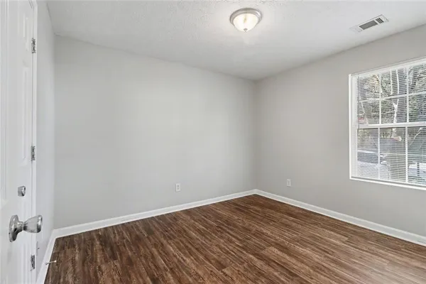an empty room with wooden floor and windows