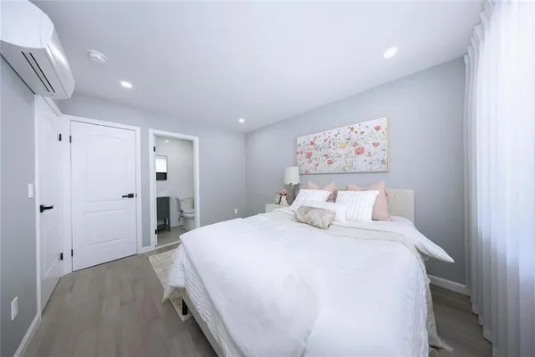 a spacious bedroom with a bed and a painting on the wall