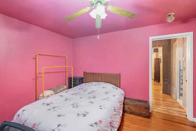 a bedroom with a bed and a dresser with wooden floor