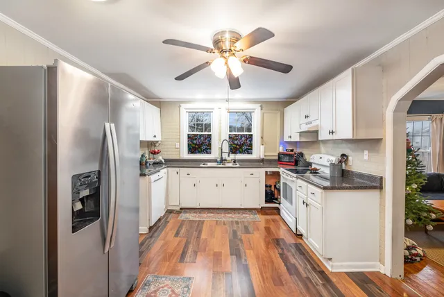 a kitchen with stainless steel appliances a refrigerator a sink dishwasher a stove and white cabinets with wooden floor