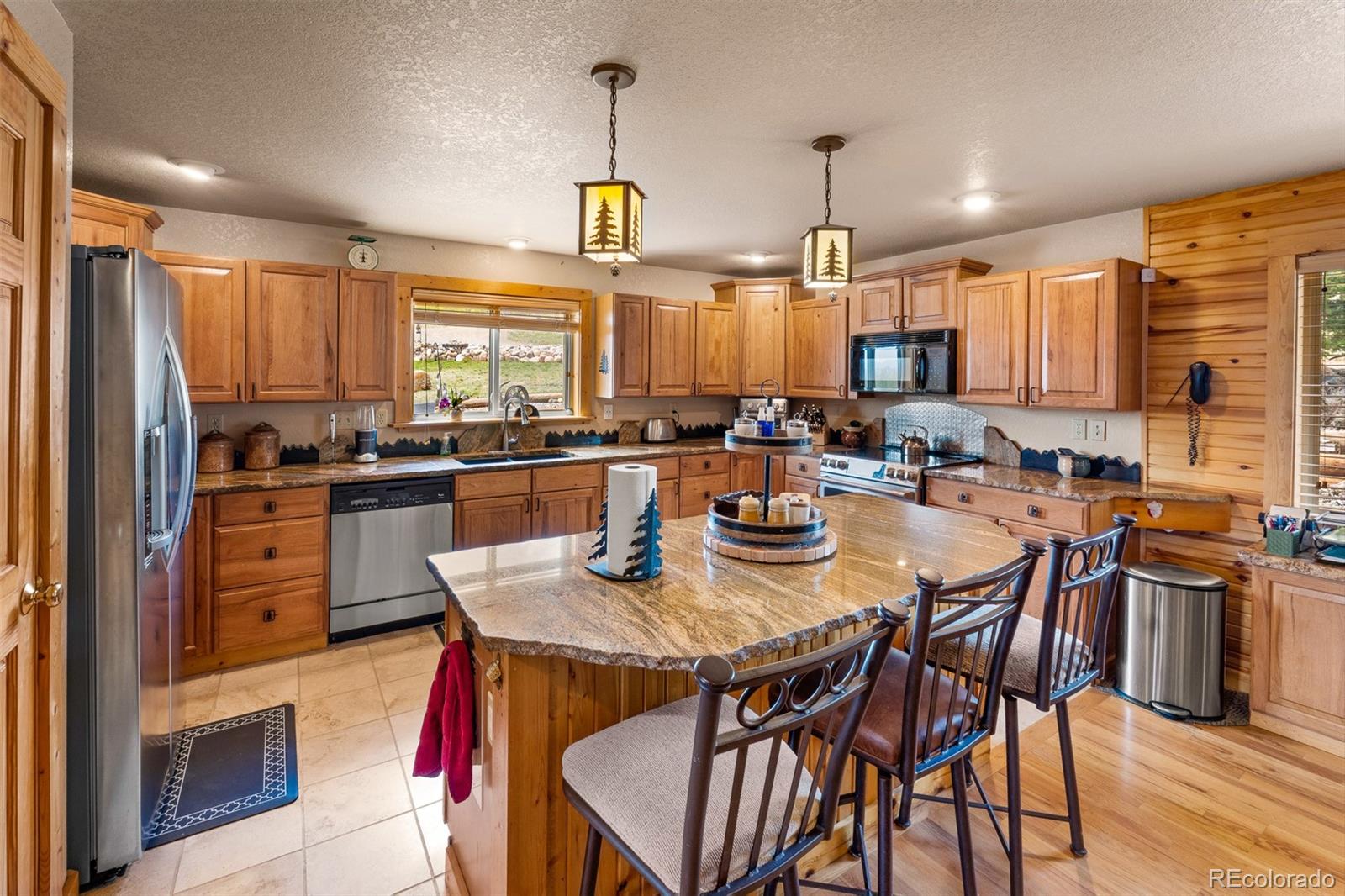 1163 Michigan Hill Road Jefferson, CO 80456 - Photo 3 of 48 a kitchen with stainless steel appliances kitchen island granite countertop a stove a refrigerator a sink a dining table and chairs with wooden floor