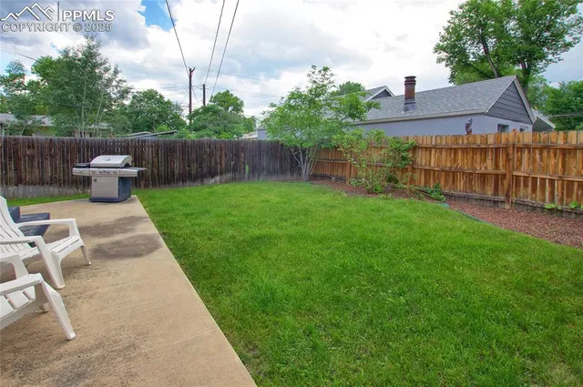 a view of backyard with deck and wooden fence