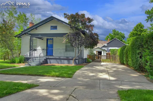 a front view of a house with a garden and trees