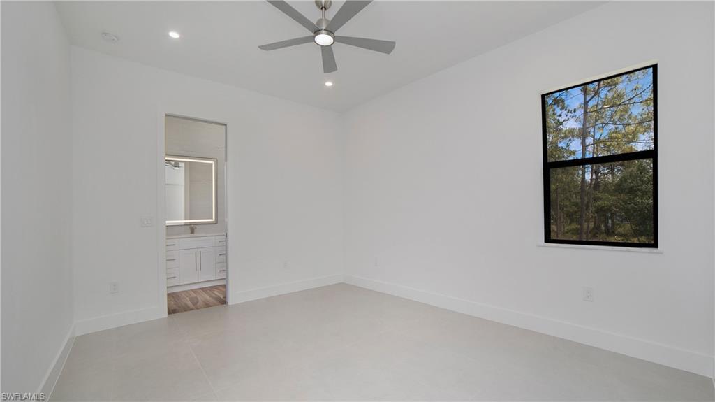 2343 Oil Well Road Naples, FL 34120 - Photo 14 of 46 Bright room with light tile flooring, a window offering a wooded landscape, and a ceiling fan with integrated lighting