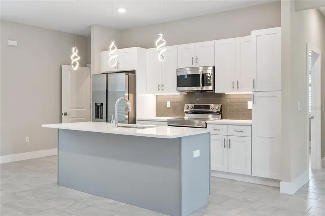 a kitchen with stainless steel appliances a refrigerator stove a sink and white cabinets