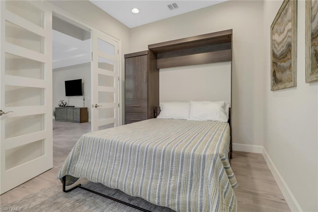 5782 Highbourne Drive Naples, FL 34113 - Photo 13 of 31 a bedroom with a bed and a flat tv screen on wall