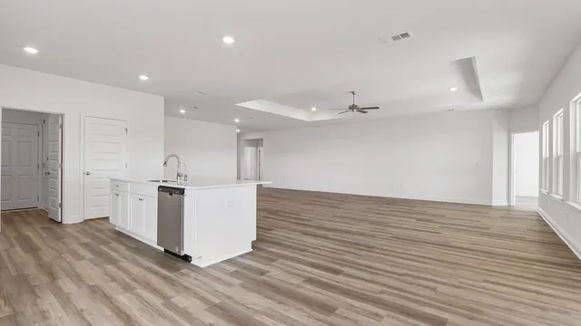 an empty room with wooden floor and kitchen view