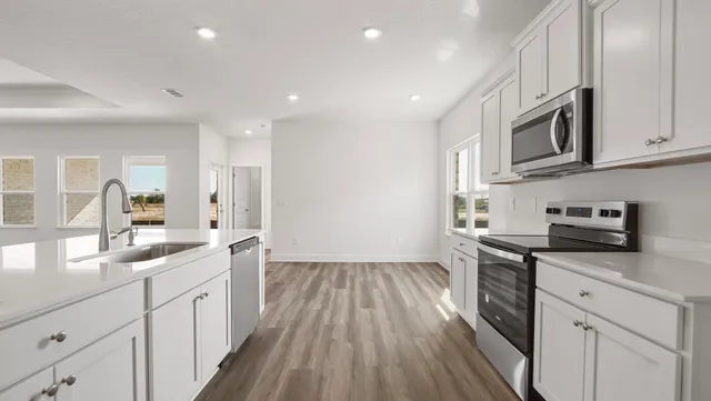 a large kitchen with stainless steel appliances granite countertop a lot of counter space and wooden floors