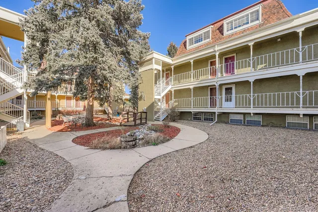 a front view of a building with balcony and trees
