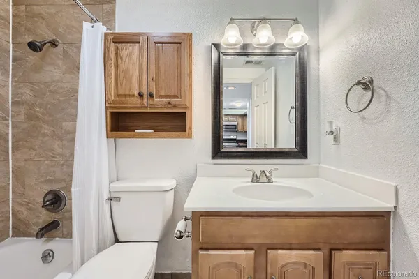 a bathroom with a granite countertop toilet a sink and a mirror