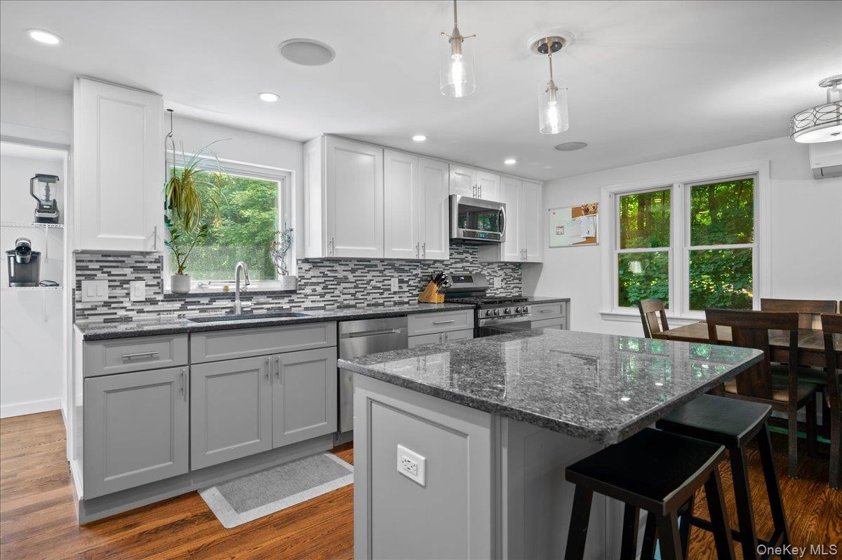 105 High St Extension Mount Kisco, NY 10549 - Photo 19 of 38 a kitchen with kitchen island granite countertop a table chairs sink and microwave