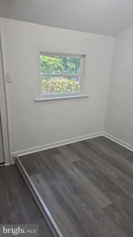 an empty room with wooden floor and window