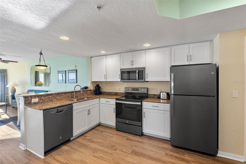 12000 Gulf Boulevard, Unit 501W Treasure Island, FL 33706 - Photo 13 of 36 a kitchen with a refrigerator a sink and wooden cabinets