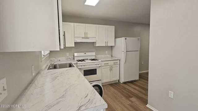 a kitchen with a stove a refrigerator and white cabinets