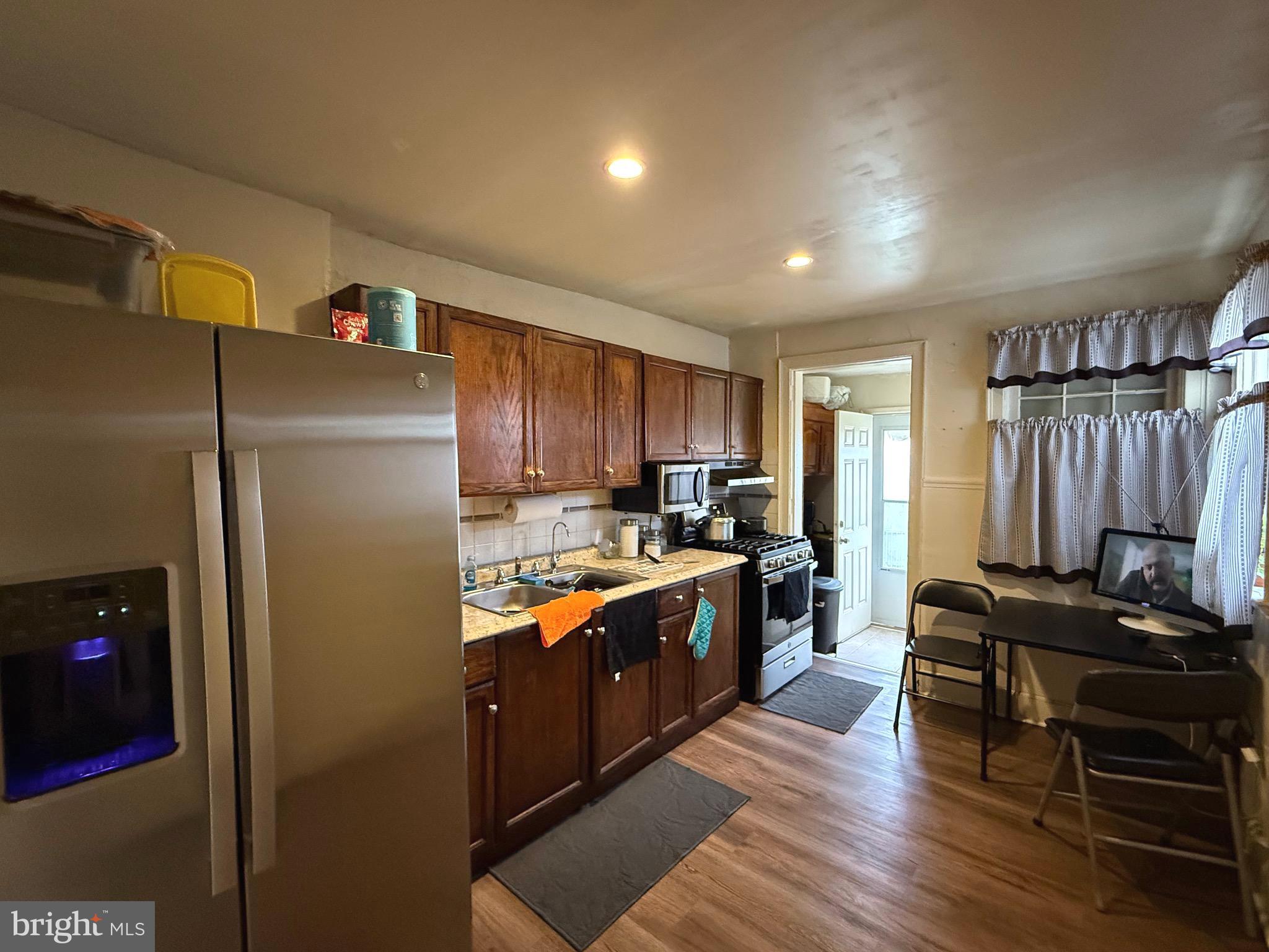 1623 Olympia Road Camden, NJ 08104 - Photo 6 of 23 a kitchen with stainless steel appliances granite countertop a refrigerator a sink dishwasher a stove and a dining table with wooden floor