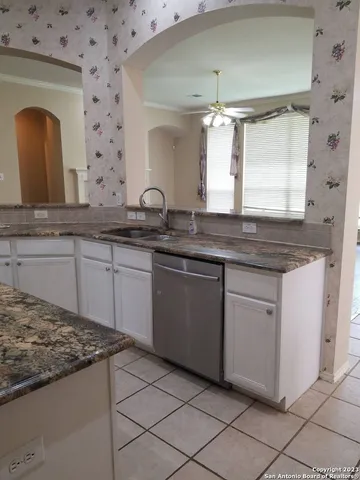 a kitchen with granite countertop a sink and white cabinets