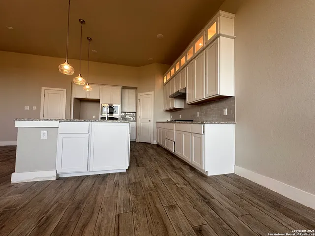 a kitchen with stainless steel appliances granite countertop a stove a sink dishwasher and a refrigerator with wooden floor