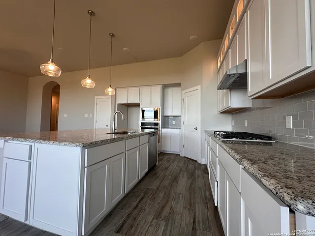 a kitchen with stainless steel appliances granite countertop a stove a sink and a refrigerator