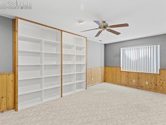 7590 Julynn Road Colorado Springs, CO 80919 - Photo 17 of 44 Carpeted empty room with ceiling fan and wood walls
