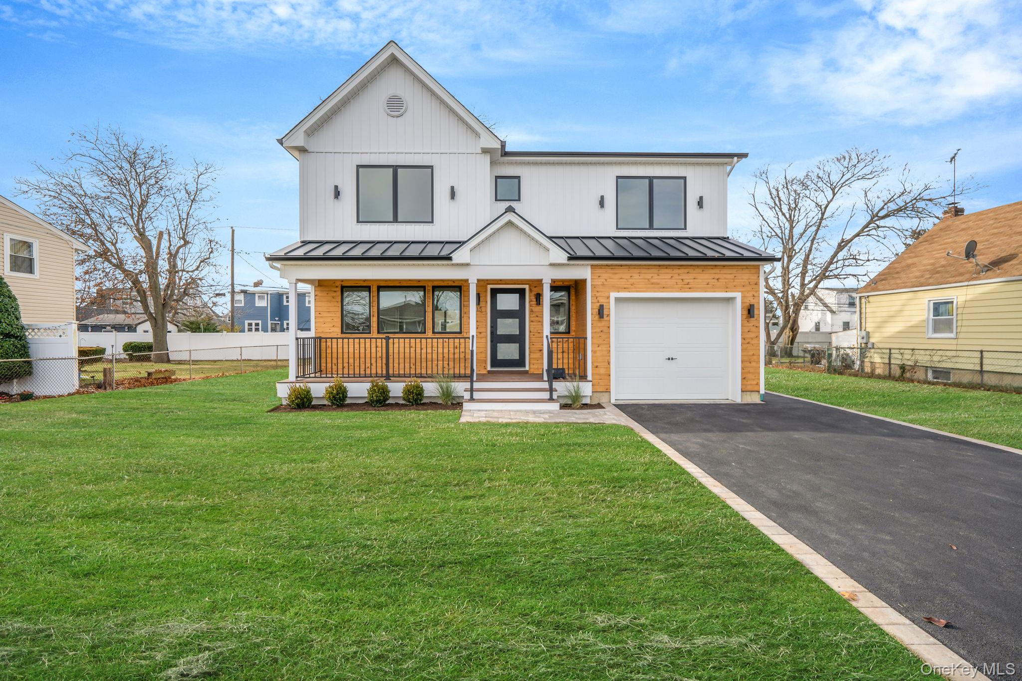 View of front of property featuring a standing seam roof, a porch, driveway, a metal roof, and an attached garage