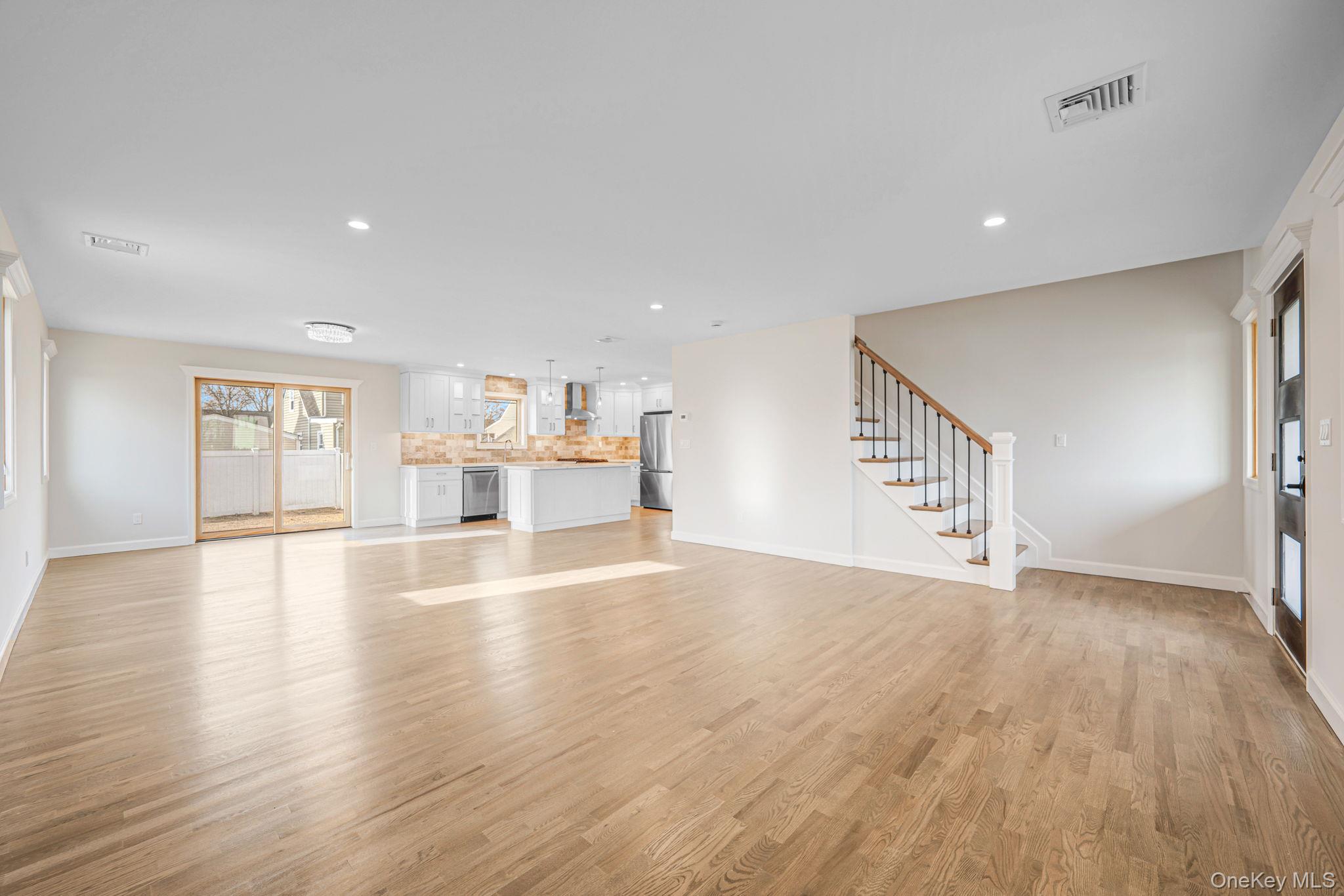 115 Riviera Parkway Lindenhurst, NY 11757 - Photo 24 of 33 Unfurnished living room featuring healthy amount of natural light, light wood-style flooring, recessed lighting, and stairway