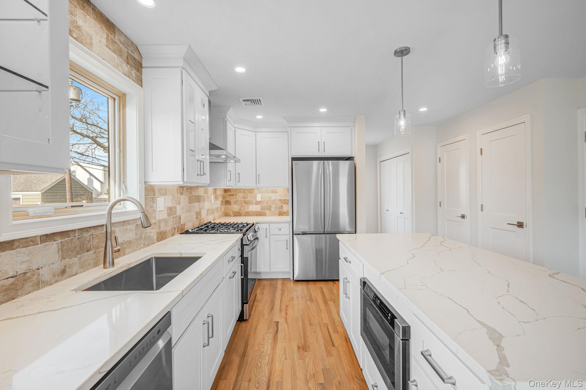 115 Riviera Parkway Lindenhurst, NY 11757 - Photo 31 of 33 Kitchen featuring appliances with stainless steel finishes, light stone countertops, white cabinets, decorative light fixtures, and recessed lighting